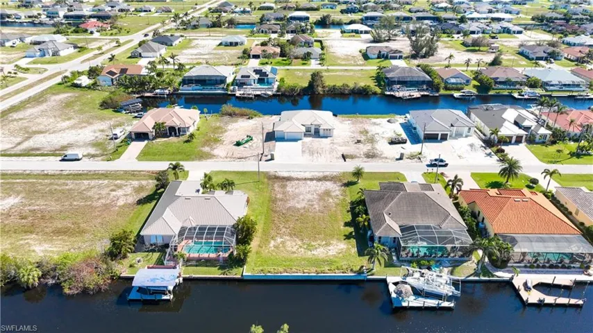 Canal-front property featuring a private boat dock with a covered lift and screened-in swimming pool