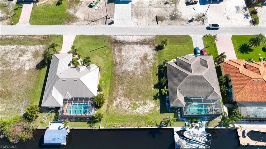 Expansive cleared lot bordered by paved roadways and existing residential properties