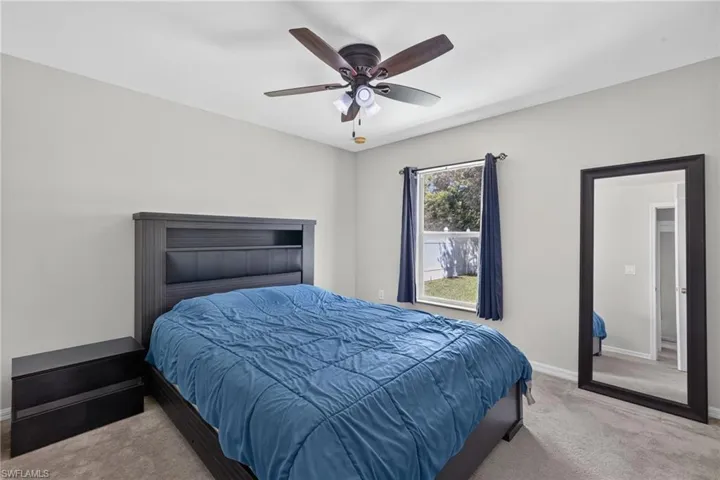 Guest bedroom with neutral-toned room featuring wall-to-wall carpeting, a multi-blade ceiling fan with integrated lighting, and a single-hung window