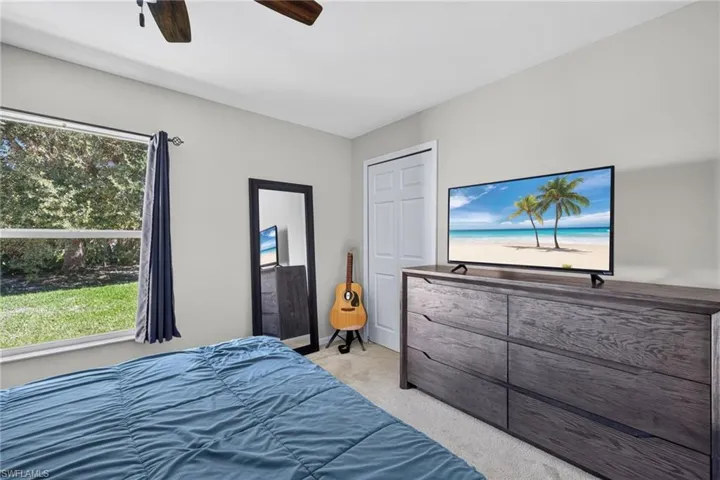 Neutral-toned walls, carpeting, a single-hung window, a white six-panel closet door, and a ceiling fan