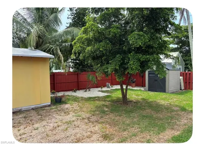 Fenced backyard featuring a storage unit
