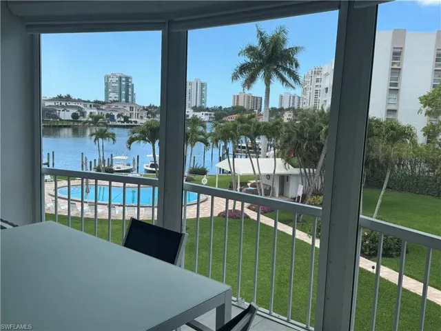 Balcony featuring view of pool, outdoor dining space, and a water view
