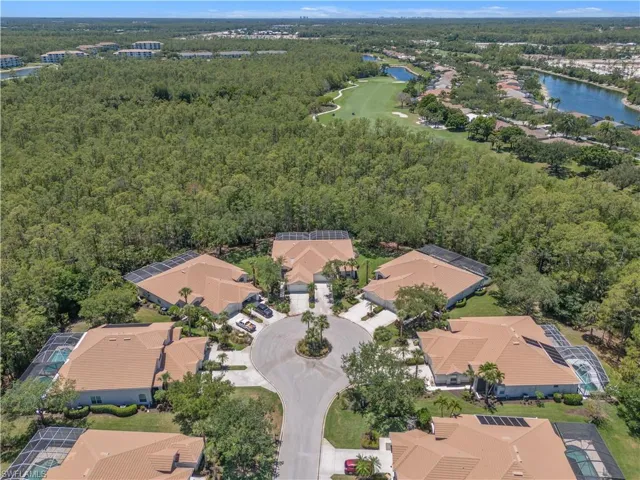 Aerial perspective of suburban area with a large body of water, a forest, and a golf course