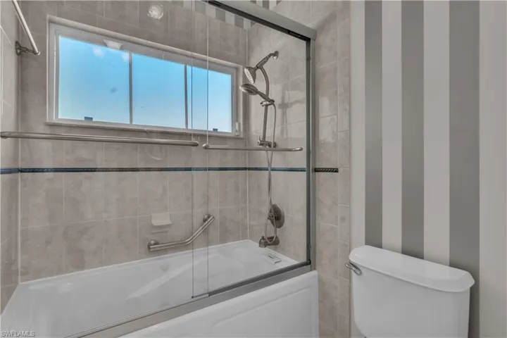 Full bath with shower / bath combination with glass door and toilet