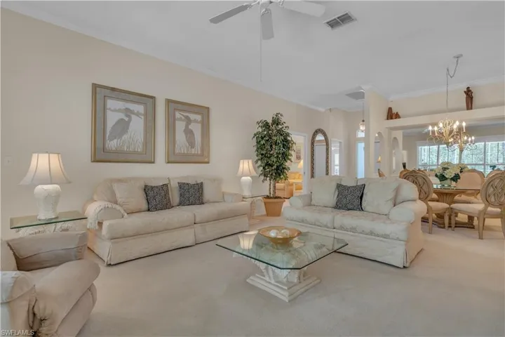 Living room featuring carpet, crown molding, a chandelier, and a ceiling fan