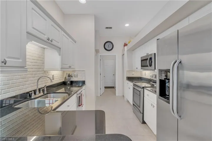 Kitchen with stainless steel appliances, a sink, backsplash, white cabinets, and recessed lighting