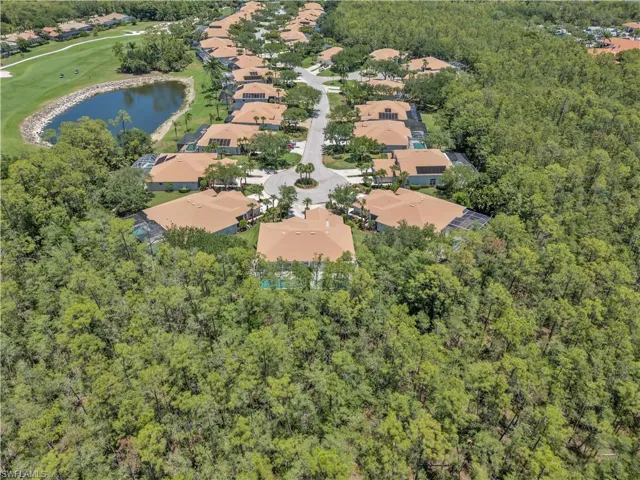 Aerial view of property and surrounding area with nearby suburban area, a large body of water, a forest, and a golf course
