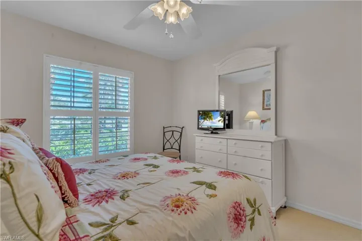 Bedroom with light colored carpet, ceiling fan, and baseboards