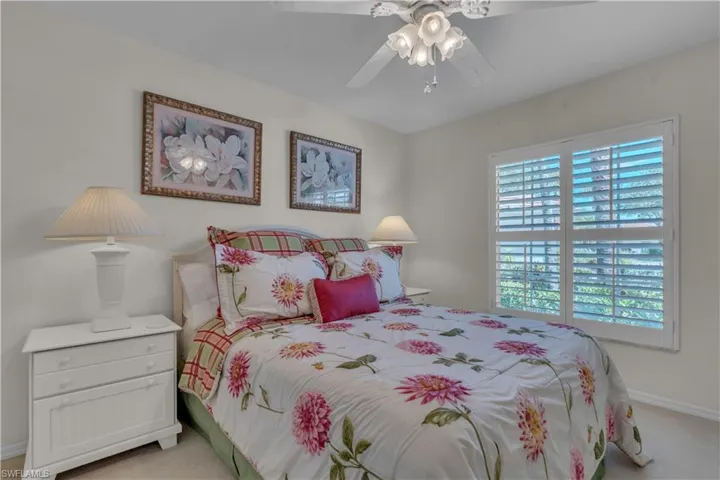 Bedroom with light colored carpet, baseboards, and a ceiling fan