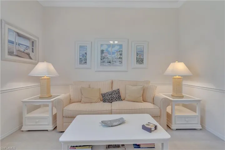 Living area with carpet flooring, baseboards, and crown molding