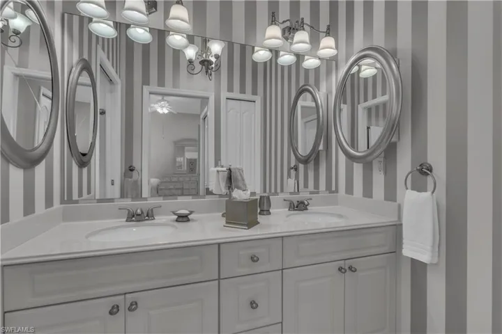 Full bathroom with wallpapered walls and double vanity