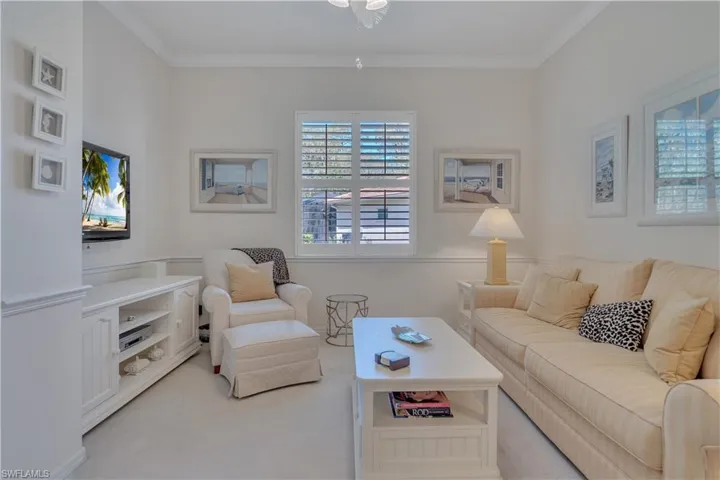 Living area with plenty of natural light, light carpet, crown molding, and ceiling fan
