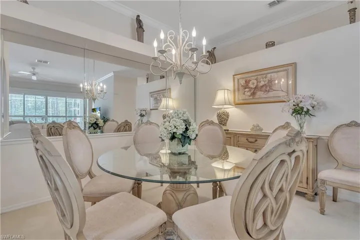 Carpeted dining space with a chandelier, ornamental molding, and ceiling fan