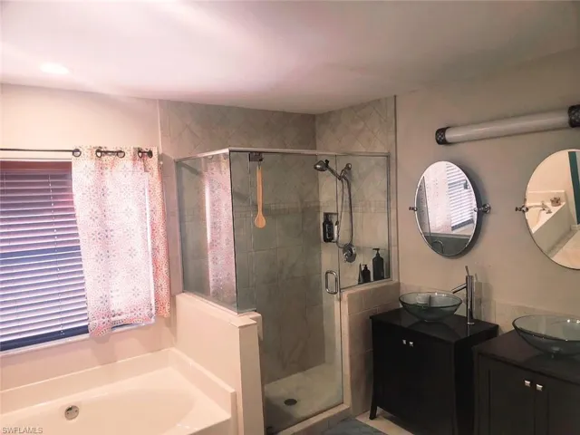Bathroom featuring double sink vanity and shower with separate bathtub