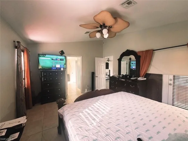 Bedroom with light tile patterned flooring, vaulted ceiling, and ceiling fan