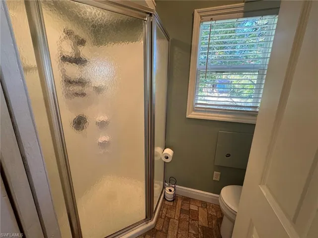 Bathroom featuring a shower with door and toilet