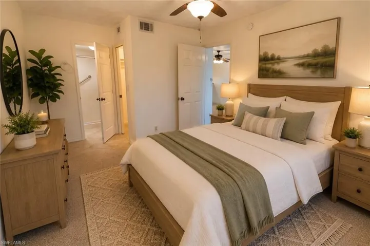 Carpeted bedroom featuring a ceiling fan with integrated lighting, two white panel doors, and a decorative wall art piece