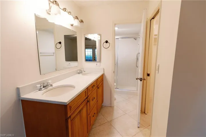 Dual vanity with light wood cabinetry, white countertops, and undermount sinks