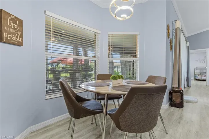Dining space with a chandelier, ornamental molding, and light wood-type flooring