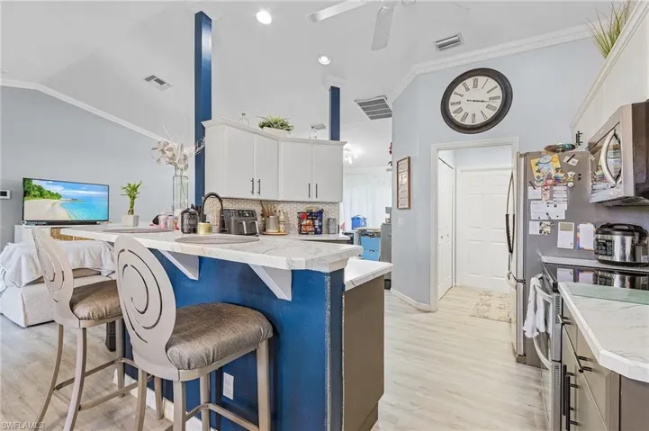 Kitchen featuring vaulted ceiling, light hardwood / wood-style flooring, backsplash, electric range oven, and white cabinets