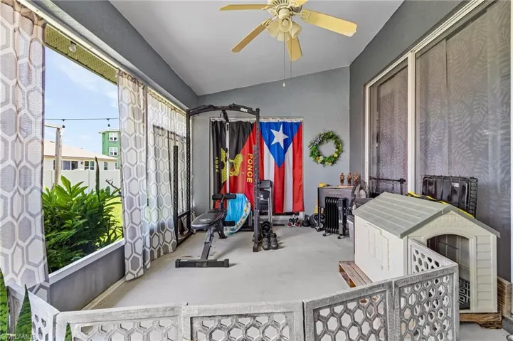Exercise room with carpet floors, ceiling fan, and vaulted ceiling