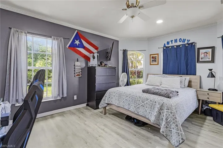 Bedroom with ceiling fan, multiple windows, and wood-type flooring