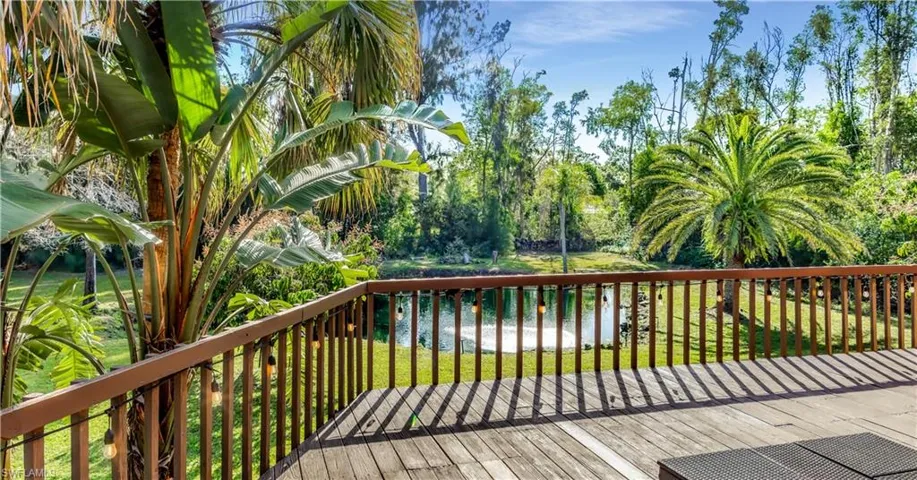 Wooden terrace featuring a water view and a yard