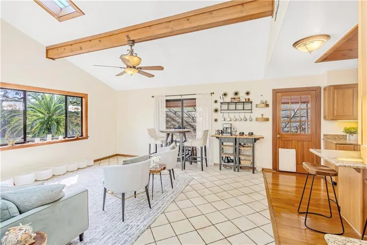 Living room featuring vaulted ceiling with skylight, ceiling fan, and light hardwood / wood-style flooring