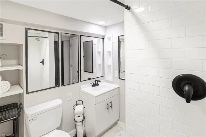 Bathroom with a tile shower, vanity, and toilet