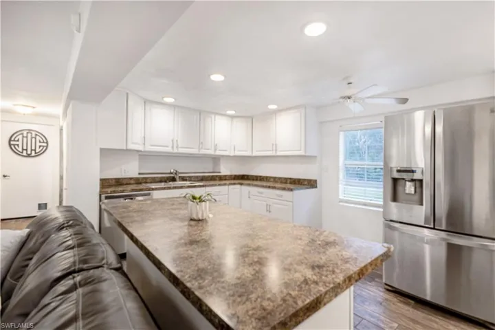 Kitchen featuring stainless steel appliances, white cabinetry, sink, hardwood / wood-style flooring, and ceiling fan