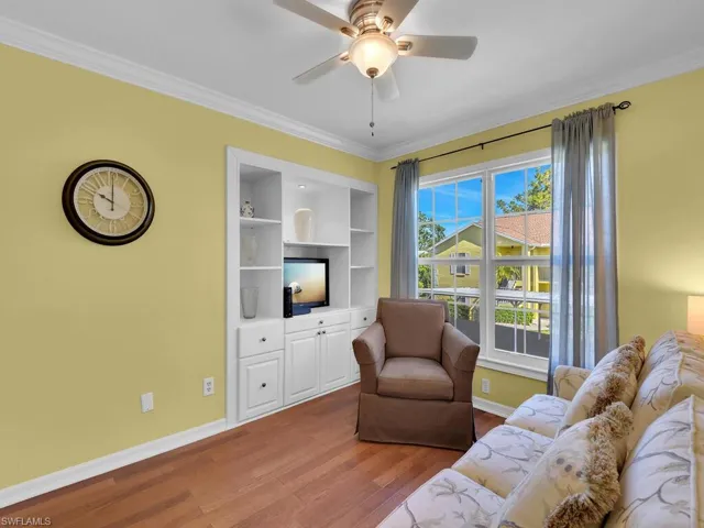 Living area with ornamental molding, wood finished floors, and a ceiling fan