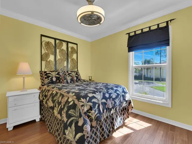 Bedroom featuring wood finished floors and crown molding