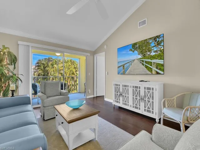 Living area with lofted ceiling, ornamental molding, and wood finished floors