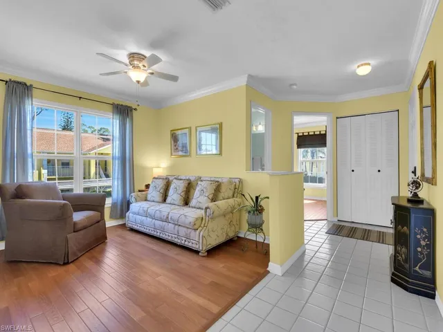 Living area featuring crown molding, light wood-style flooring, and ceiling fan