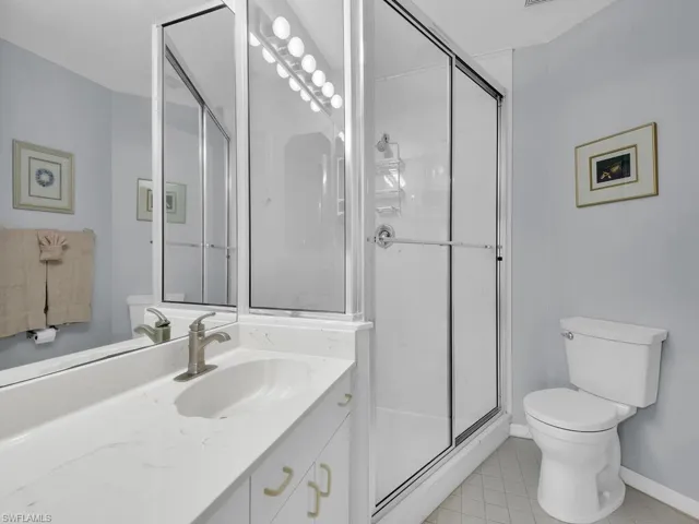 Bathroom with light tile patterned floors, vanity, and a stall shower