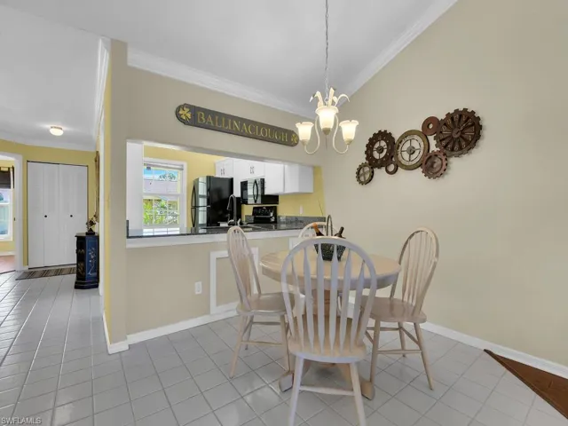 Dining space with crown molding, a chandelier, and light tile patterned flooring