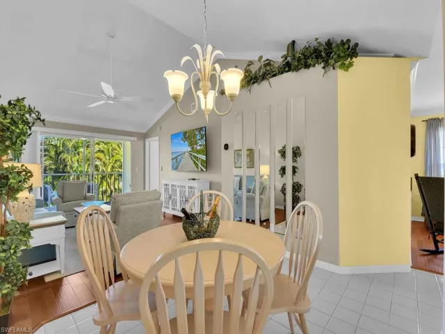 Dining room featuring ornamental molding, vaulted ceiling, a chandelier, a ceiling fan, and wood finished floors
