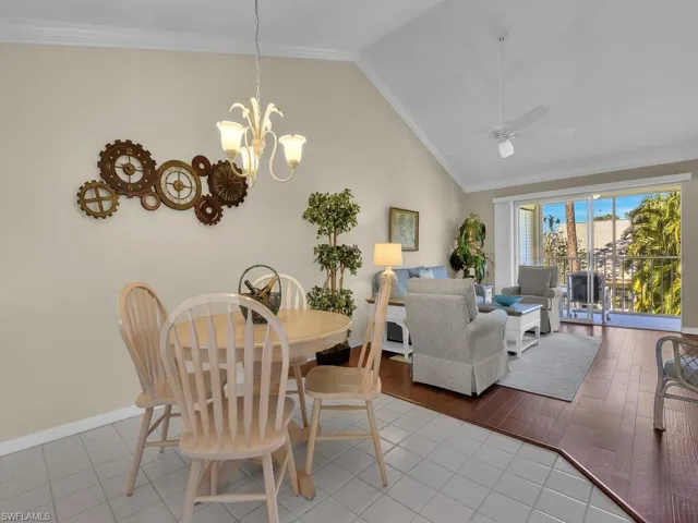 Dining room with ornamental molding, tile patterned floors, vaulted ceiling, a ceiling fan, and a chandelier