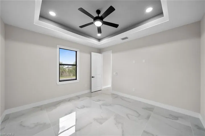Tiled spare room featuring ceiling fan and a raised ceiling