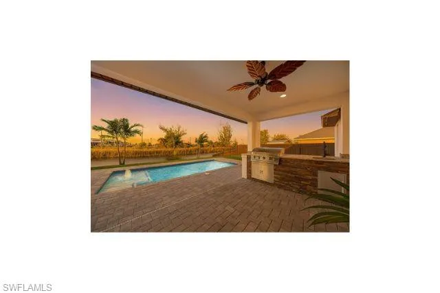 Pool at dusk featuring area for grilling, a ceiling fan, a patio, and an outdoor pool