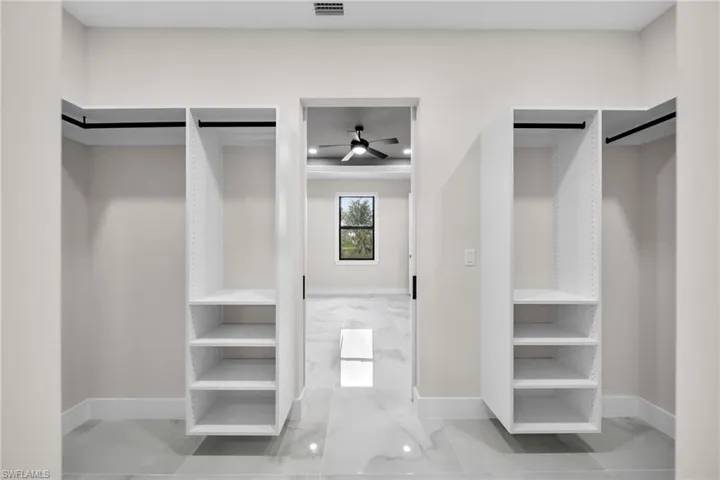 Walk in closet featuring a barn door, tile patterned floors, and ceiling fan