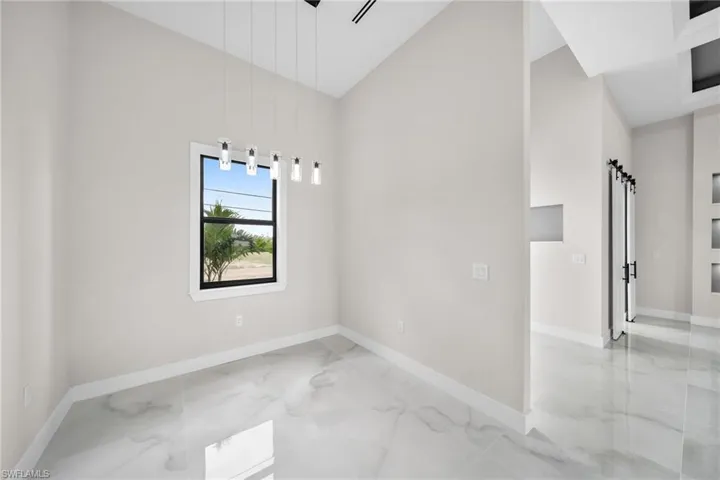 Unfurnished room featuring high vaulted ceiling, a barn door, and tile patterned flooring