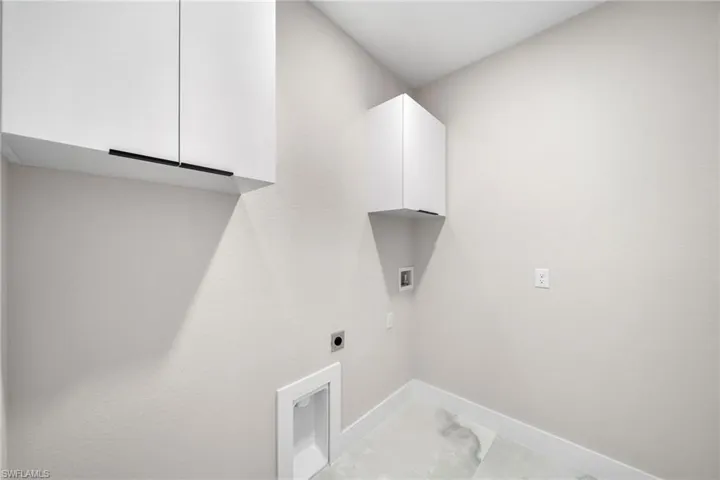 Washroom with cabinets, hookup for a washing machine, hookup for an electric dryer, and light tile patterned flooring