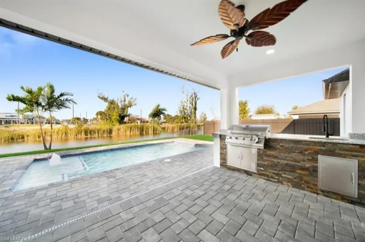 View of patio with a fenced in pool, exterior kitchen, grilling area, and ceiling fan
