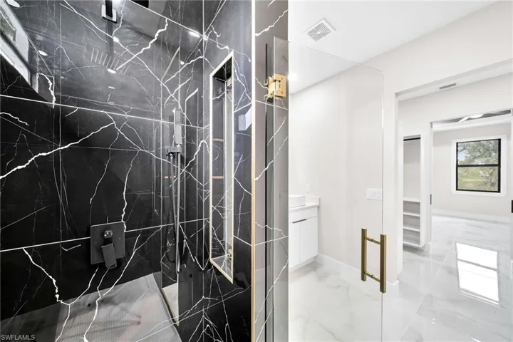 Bathroom featuring vanity, walk in shower, and tile patterned flooring