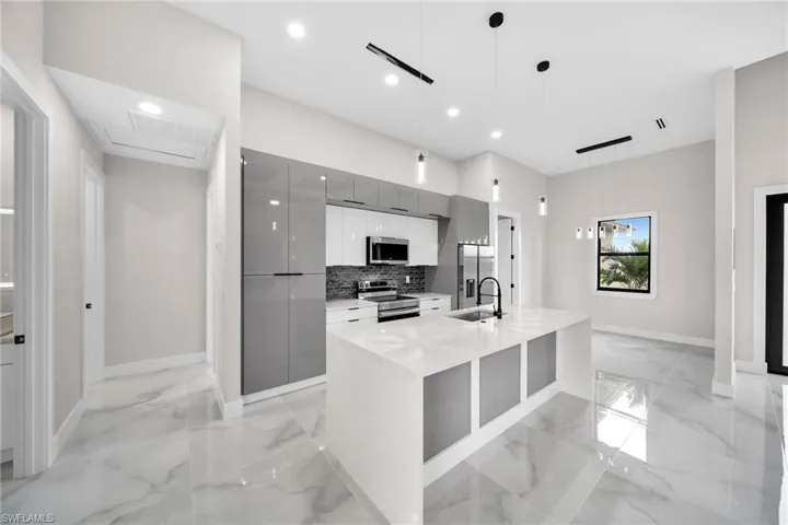 Kitchen with stainless steel appliances, a kitchen island with sink, light tile patterned flooring, gray cabinets, and tasteful backsplash