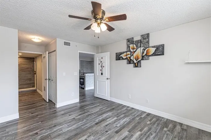 Unfurnished bedroom featuring a textured ceiling, wood finished floors, a ceiling fan, and a closet