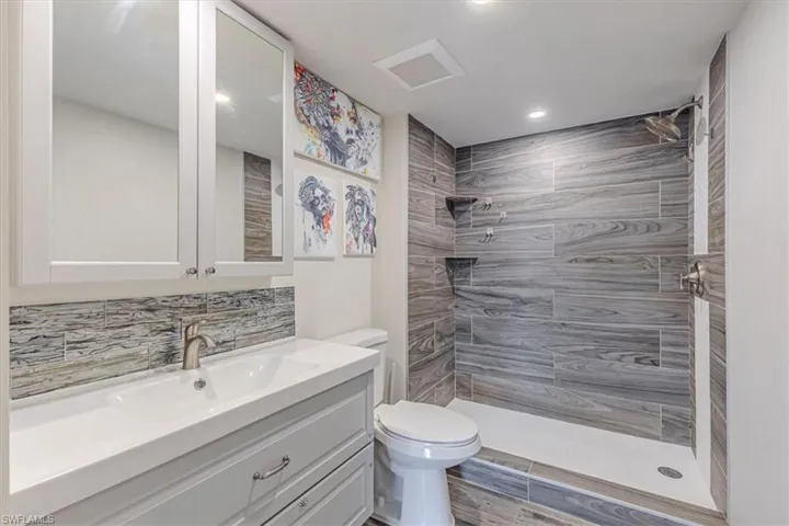 Bathroom featuring a shower stall, vanity, tasteful backsplash, recessed lighting, and light wood-style floors