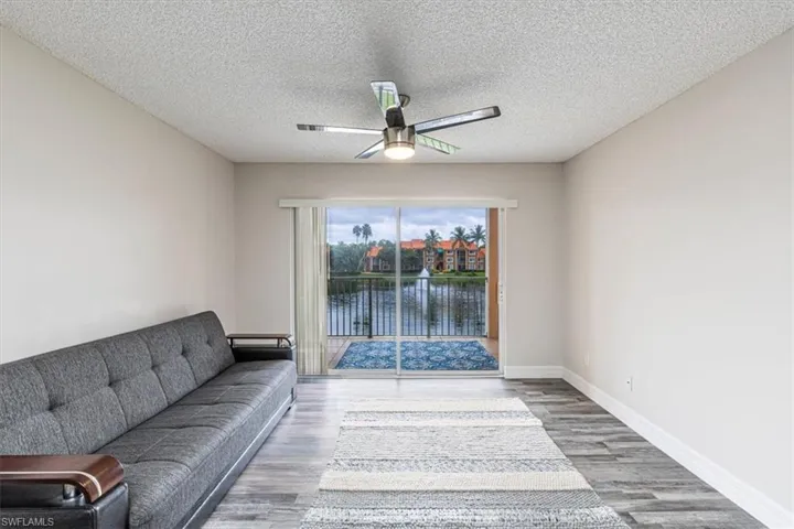 Living area featuring a water view, wood finished floors, a textured ceiling, and ceiling fan