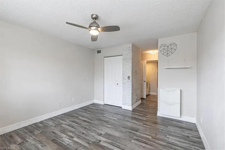 Unfurnished bedroom featuring a textured ceiling, dark wood-style flooring, ceiling fan, and a closet
